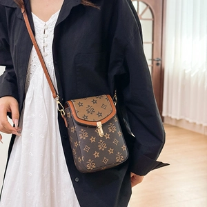 Close-up of vintage patterned crossbody phone bag with gold clasp and leather strap