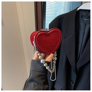 Detail of red heart mini leather bag with embossed lettering and silver bead chain strap