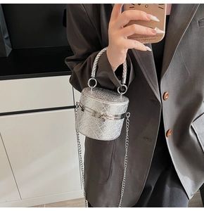 Detail der silbernen Pailletten-Eimertasche mit gewebtem Metallgriff und Kette