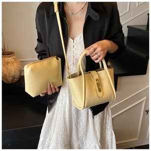 Detailed view of yellow faux crocodile bucket bag with golden hardware and inner pouch