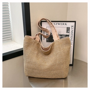Detail of hand-woven straw tote bag with wide fabric shoulder straps for summer beach use