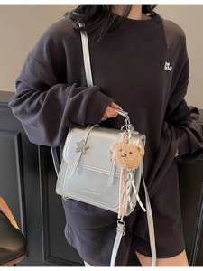Silver metallic mini backpack with star detail and plush bear charm worn on hoodie