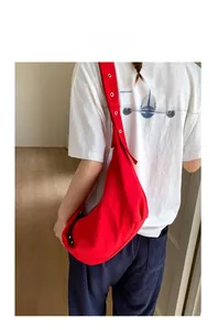 Detail of red canvas hobo bag showing the adjustable wide strap and crescent shape
