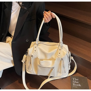 Dettaglio della grande borsa tote crema con design multitasche e dettagli in argento