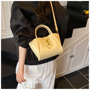 Detail of cream bucket bag with crocodile embossed texture and elegant gold metal lock