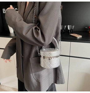 Detail of silver sequin bucket bag with chain strap and woven top handle on model