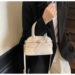 Détail d'un sac à main beige en cuir grainé avec boucle en métal et bandoulière fine