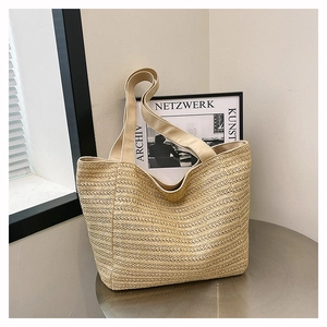 Detail of hand-woven straw tote bag with textured stripes on a silver round table
