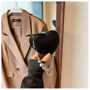 Detail of a mini heart-shaped black leather bag featuring a silver beaded metal chain