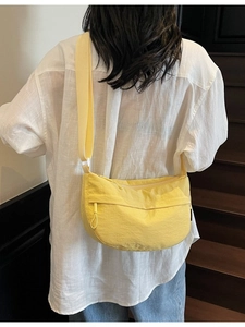 Back view of a yellow nylon crescent crossbody bag with wide shoulder strap on a model