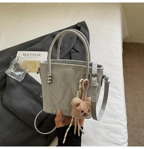Secchiello grigio con charm a forma di orso accanto a un libro d'arte di Matisse