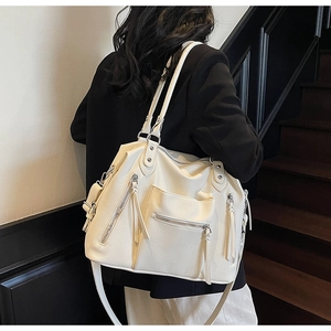 Detail of off-white lychee textured leather tote bag with stylish zipper and tassel accents