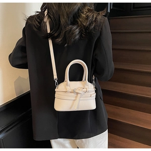 Détail du sac beige en cuir grainé avec boucle décorative et bandoulière amovible