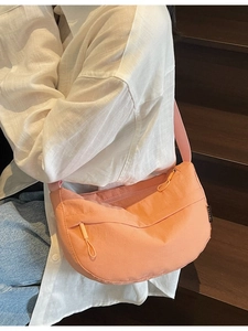 Peach pink nylon half-moon crossbody bag with adjustable strap and casual minimalist style
