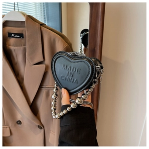 Close-up of black heart-shaped leather mini bag with silver bead handle and chain strap