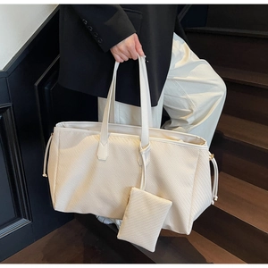 Détail du sac cabas tressé blanc cassé avec mini pochette assortie sur un escalier