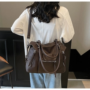 Model view of large dark brown leather tote bag with long tassels and silver zipper detail