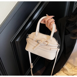 Détail d'un mini sac beige en cuir grainé avec boucle décorative et bandoulière chic