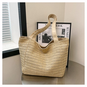Close-up of beige woven texture and sturdy canvas strap on a large straw tote bag