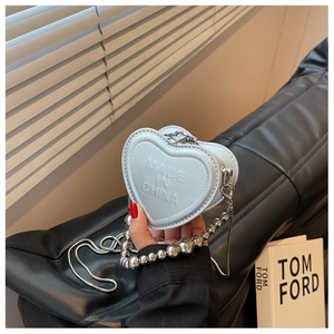 Detail of silver heart-shaped mini bag with metallic texture and chunky bead strap