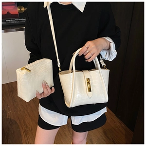 Detail view of cream white croc-embossed bucket bag with golden buckle and strap