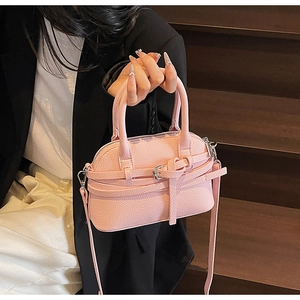 Sac à main rose texture litchi avec détail de boucle sur un escalier en bois sombre