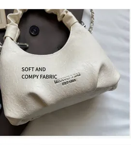 Détail de la texture gaufrée et du logo argenté sur le sac à main blanc plissé