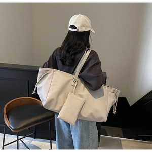 Détail d'un grand sac cabas texturé avec une petite pochette assortie sur la sangle