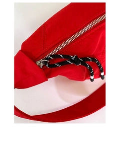 Detailed macro view of red nylon bag featuring silver metal zipper and woven puller