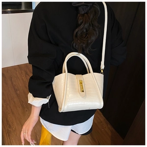 Detail of cream white faux crocodile leather bucket bag with gold clasp and top handle