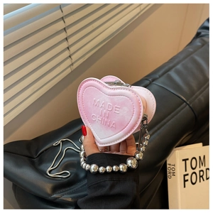 Pink heart-shaped mini purse with bead handle and silver chain strap shown held by hand