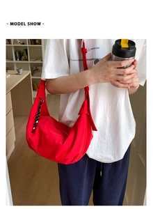Detail of red crescent shoulder bag with woven zipper pull and adjustable strap