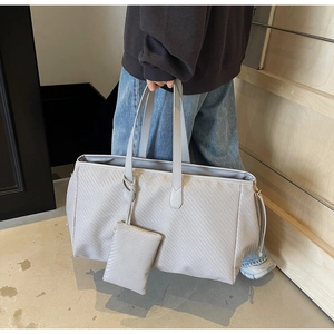 Détail d'un grand sac fourre-tout gris clair avec texture tissée et pochette assortie