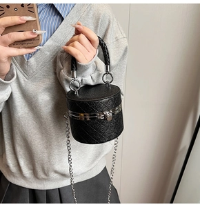 Detail der schwarzen gesteppten Beuteltasche mit Silberkette und geflochtenem Griff