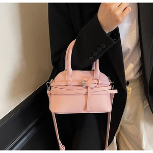 Gros plan du sac coquillage rose à grain litchi avec boucle et poignée ronde