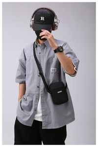 Detail shot of a black minimalist crossbody phone bag paired with a grey utility shirt