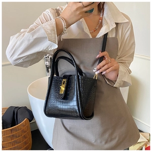 Close-up of black crocodile texture bucket bag with gold twist lock and dual handles
