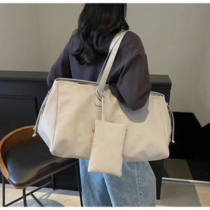 Détail du grand sac cabas tissé avec mini pochette assortie et cordons de serrage latéraux