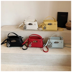 Five trapezoidal handbags in various colors with metallic twist locks and heart charms