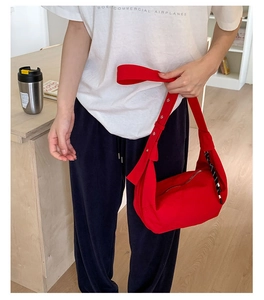 Detail of red nylon canvas crossbody bag with wide strap and silver metal eyelets