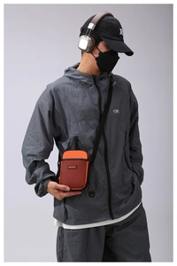 Detail view of the orange mesh pocket and MACHUGE brand label on small crossbody bag