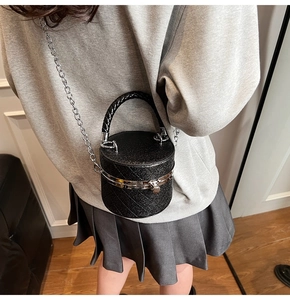 Detail view of mini black cylindrical bucket bag with silver chain and quilted texture