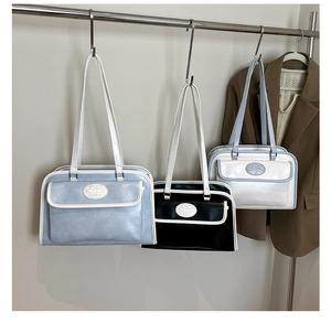 Détail de sacs cabas en cuir brillant en bleu, noir et blanc sur un cintre élégant