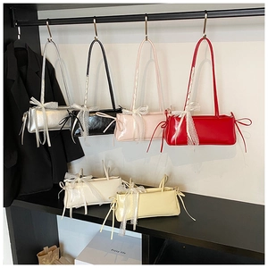Multiple glossy shoulder bags with lace bow details on display in various vibrant colors