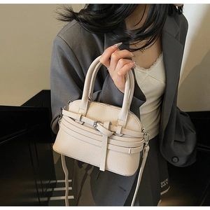 Détail d'un sac en cuir beige avec texture grainée et boucle décorative élégante