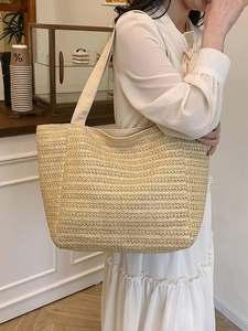 Minimalist woven straw tote bag in beige for women, shown on a shoulder in a cafe setting