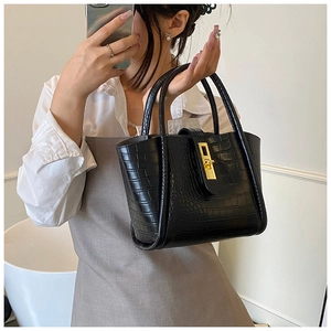 Detail of black crocodile texture bucket bag with a stylish golden metal lock