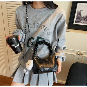 Détail du sac dumpling noir brillant avec poignée plissée nuage et bandoulière en chaîne