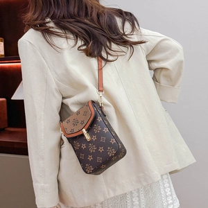 Detail view of the vintage monogram pattern and gold clasp on the brown crossbody bag