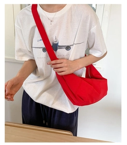 Detail of red nylon crescent crossbody bag with matching wide strap and metal zipper